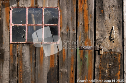 Image of Old weathered and worn wooden planks with door and pink framed window