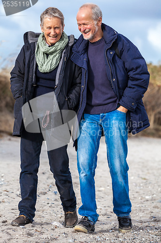 Image of happy elderly senior couple walking on beach