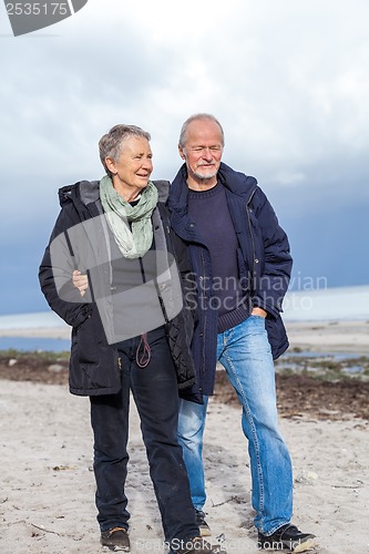 Image of happy elderly senior couple walking on beach