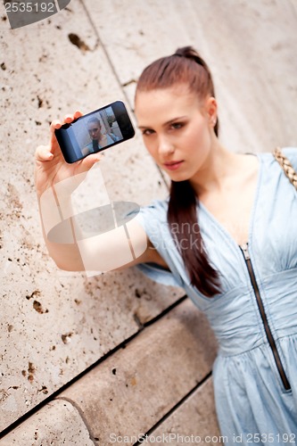 Image of attractive young woman with smartphone camera photos outdoor