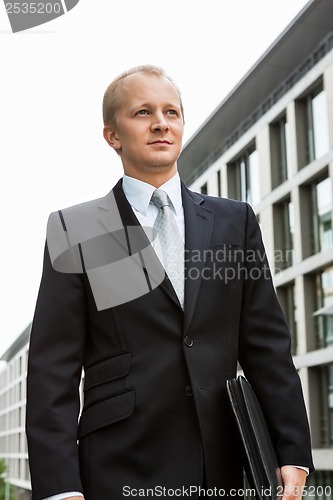 Image of smiling successful business man in black suit outdoor