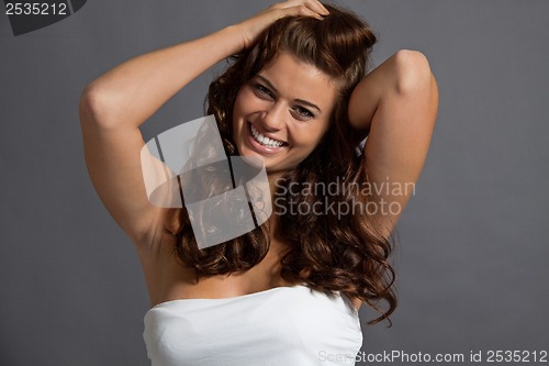 Image of smiling attractive young woman with long wavy dark hair