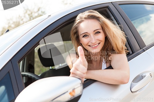 Image of young attractive happy woman sitting in car summertime