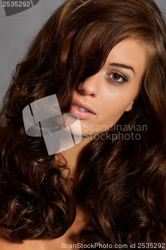 Image of young woman portrait with shiny healthy brown curly hair