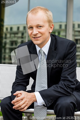 Image of smiling successful business man in black suit outdoor