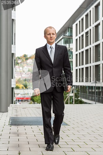 Image of smiling successful business man in black suit outdoor