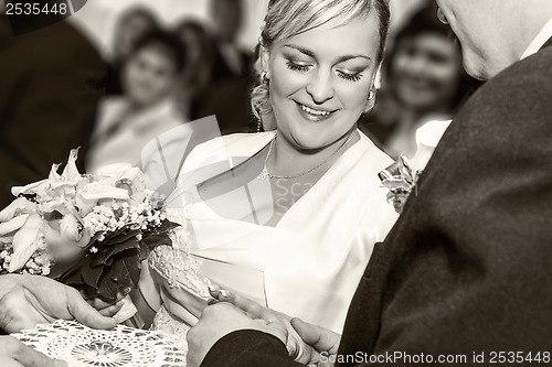 Image of Groom Happy putting ring on smiling pretty woman bride's finger