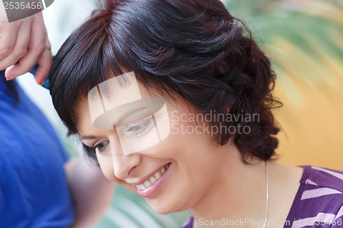 Image of stylist prepares hairstyle for beautiful woman