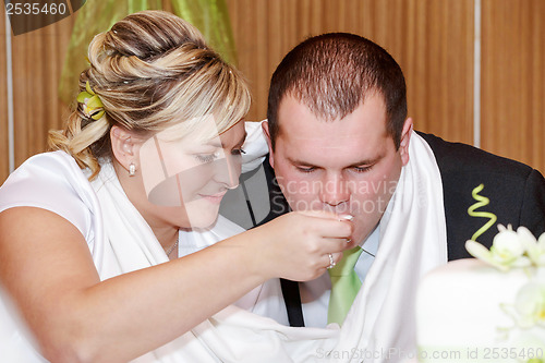 Image of bride feeding her groom with spoon on wedding lunch