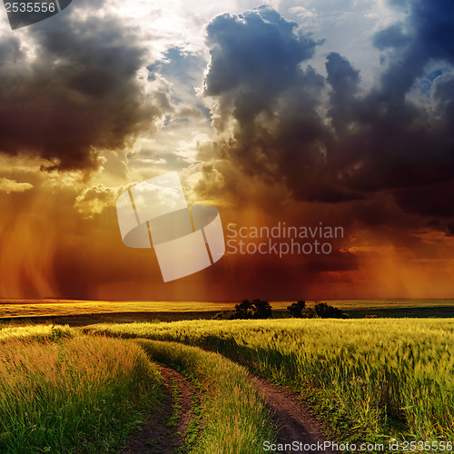 Image of dramatic cloudy sky over road in green field