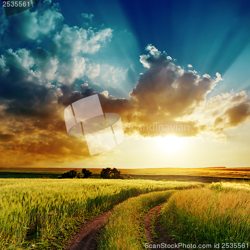 Image of dramatic sunset over rural road in green field