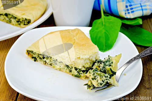 Image of Pie with spinach and cheese with a fork on a board