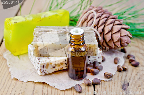 Image of Oil and soap different with cedar nuts and cone on a board