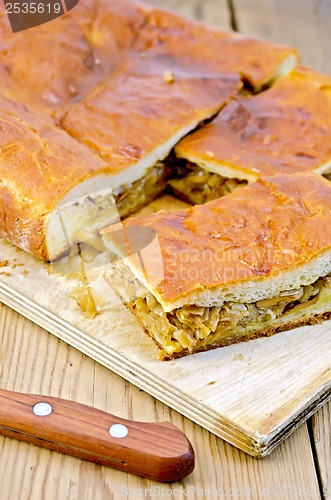 Image of Pie with cabbage and mushrooms on a board with a knife