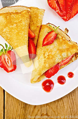 Image of Pancakes with strawberries and jam on a white plate