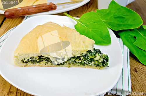 Image of Pie with spinach and cheese on the board with leaves