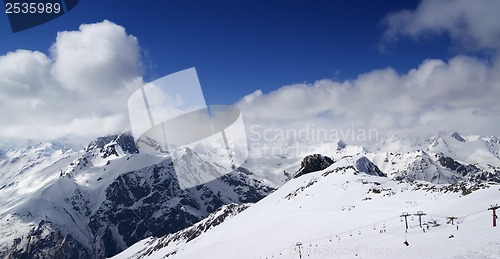 Image of Panoramic view on ski slope and cloudy mountains at nice sun day