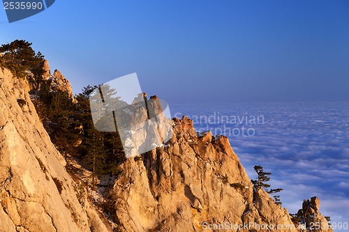 Image of Sunlit rocks and sea in clouds at evening