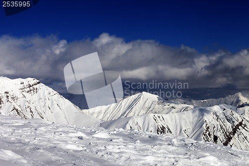 Image of Ski slope and beautiful snowy mountains in clouds.