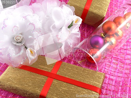 Image of Golden gift box with white flowers and christmas balls in glass