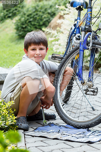 Image of Teenager repairing his bike, changing broken tyre