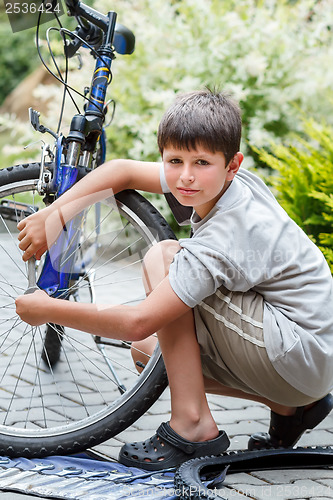 Image of Teenager repairing his bike, changing broken tyre