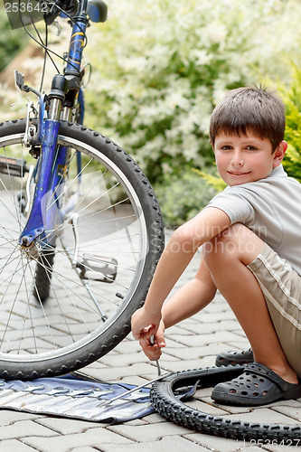 Image of Teenager repairing his bike, changing broken tyre