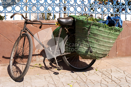 Image of Old bicycle leaning against wall with panniers on the back