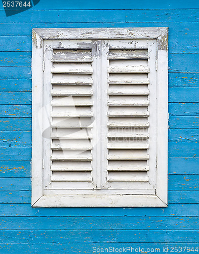 Image of Old white window with wooden shutters.