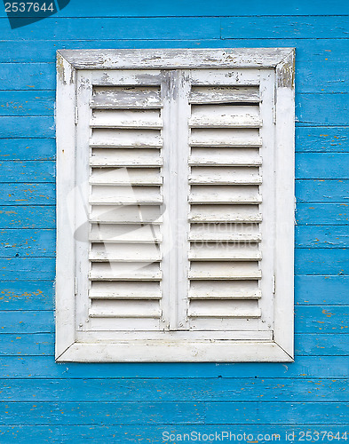 Image of Old white window with wooden shutters.