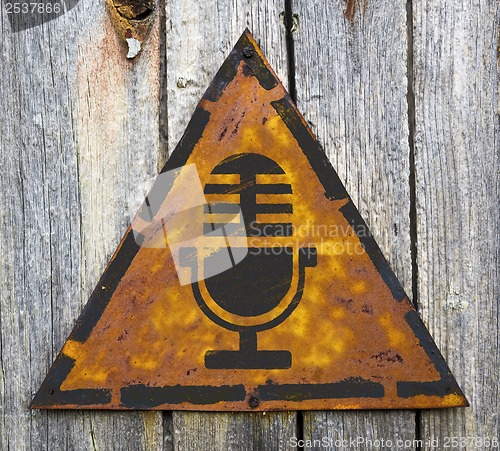 Image of Microphone Icon on Rusty Warning Sign.