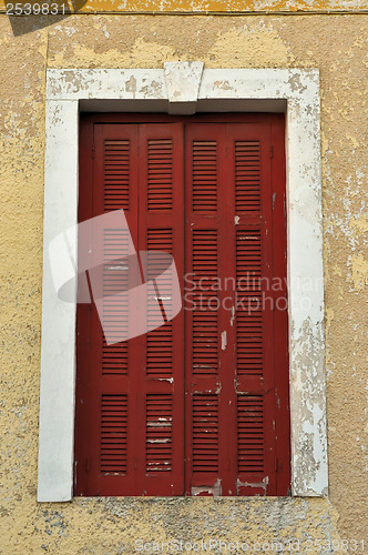 Image of closed window shutter and chipped wall