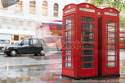 Image of Red Phone cabines in London and vintage taxi.Rainy day.