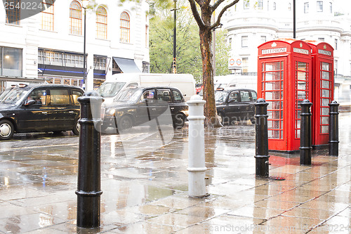 Image of Red Phone cabines in London and vintage taxi.Rainy day.