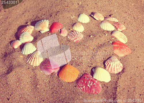 Image of heart symbol from shells on sand - vintage retro style