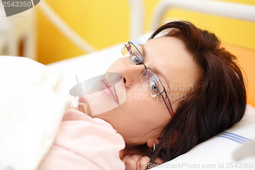 Image of sad middle-aged woman lying in hospital