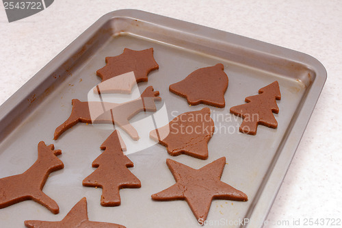 Image of Cookie sheet with uncooked festive gingerbread biscuits