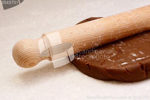 Image of Closeup of rolling pin on gingerbread biscuit dough