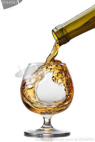 Image of Cognac pouring into glass with splash isolated on white backgrou