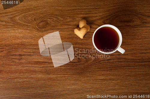 Image of hot cup of tea with cookies on wooden table