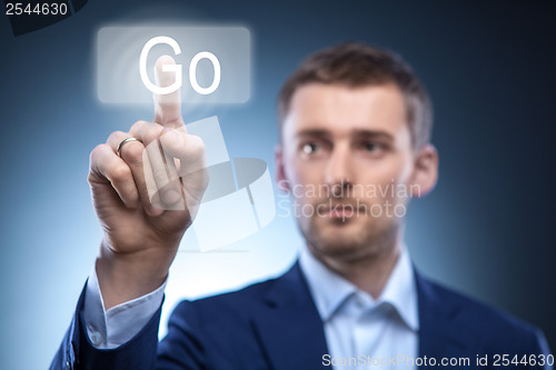 Image of business man pressing Go button on touchscreen