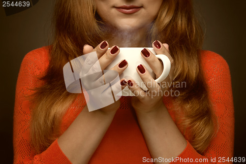 Image of woman holding hot cup and smiles