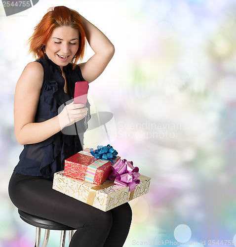 Image of Emotional smiling woman with boxes gifts and phone on a festive 