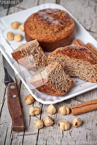 Image of sliced fresh buns, old knife,hazelnuts and cinnamon sticks 