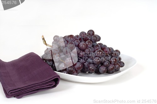 Image of A bunch of juicy red grapes on a white plate with a purple napki