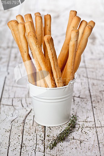 Image of white bucket with bread sticks grissini and rosemary 