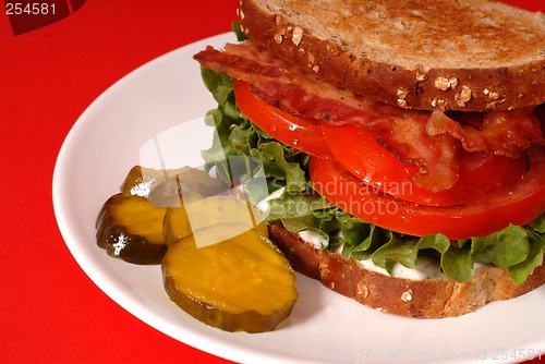 Image of Closeup of a bacon, lettuce and tomato sandwich with pickles, re