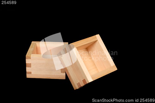 Image of Two wooden sake cups on a black background