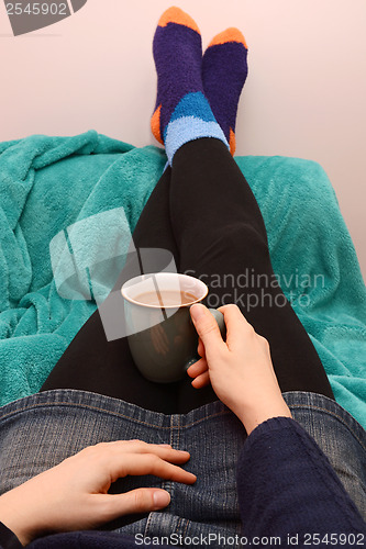 Image of Woman dressed warmly, relaxing with a hot drink