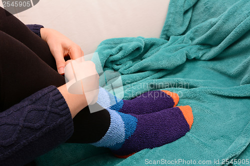 Image of Woman hugging her legs, wearing warm socks
